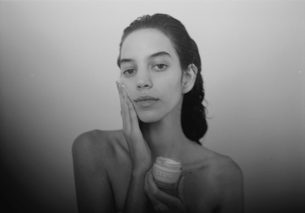 black and white photo of a woman applying skincare