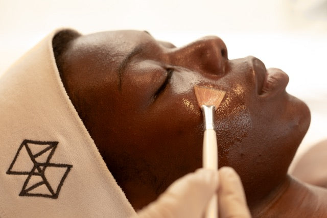 Skincare product being applied to face with a fan brush